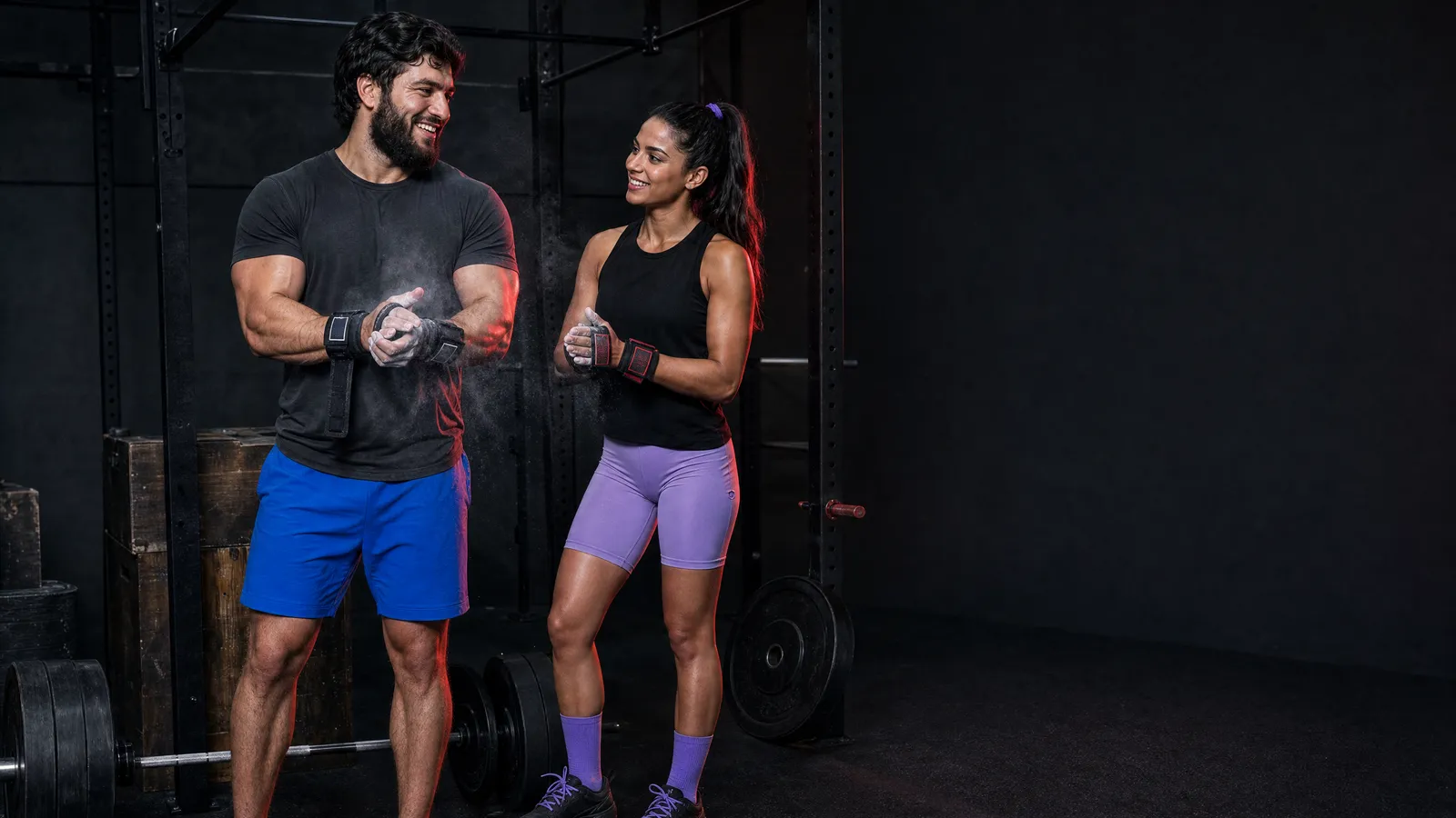 MG crew characters Shamil and Layla chalking up at the pull-up rig, Layla with wrist wraps and Shamil with lifting grips